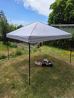 Assembled gray pop-up canopy with accessories on grass