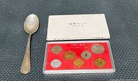 Coin set in closed slipcase beside vintage teaspoon