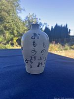 Front view showing calligraphy on beige stoneware bottle