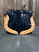 Front view of black patent leather Arcadia crossbody with beige riveted trim