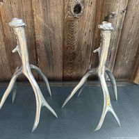 Front view of both antler candlesticks showing polished finish and overall form