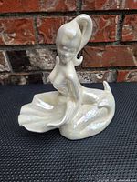 Front view of iridescent porcelain mermaid figurine with shell-like dish