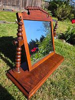 Front angled view of mahogany vanity mirror showing turned spindle supports, platform base and intact mirror glass