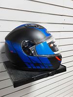 Left side view of matte black/blue HJC full-face snowmobile helmet on shelf