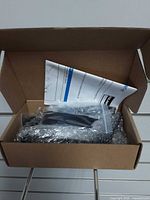 Open box showing bubble-wrapped brackets and folded instruction sheet