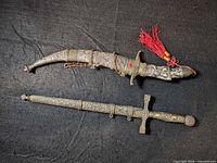 Curved dagger and straight cross-hilt dagger with sheaths displayed side by side