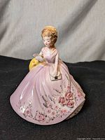 Front view of Josef Originals porcelain figurine, showing pink gown, floral detailing, purse, and letter