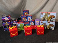 Group shot of all sealed Happy Meal toy boxes arranged on black surface