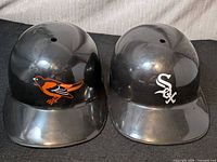 Front view of both black plastic visors with Orioles and White Sox logos