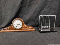 Front view of both items – mantel clock and Newton's cradle