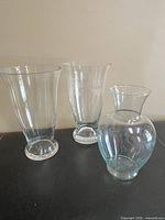 All three clear glass vases on dark surface