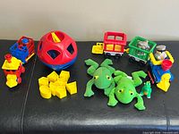 All items together on bench: Shape-O ball, train pieces, frogs, dragon