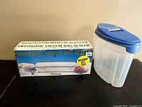 Boxed Decosonic sealer beside clear container
