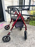 Full view of red rollator walker showing seat, wheels and storage pouch