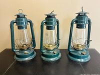 Front view of three green Dietz Blizzard No. 80 lanterns