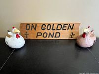 Wood sign flanked by two ceramic chicken fence sitters