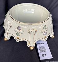 Angled view of ceramic pet dish front showing bone relief, jewels and feet