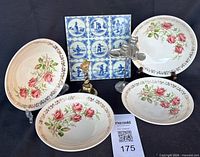 Front view of four rose plates, Delft tile panel, pewter and brass figurines