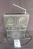 Front view showing tuning indicator, controls, speaker grille, broken antenna and power cord
