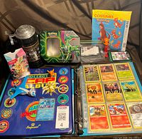 Overall lot showing binder with cards, POG binder, Blizzard stein, Pokémon tin, figures, code cards and sewing pattern