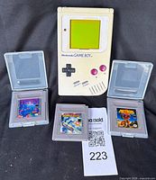 Game Boy console with three game cartridges and protective cases displayed