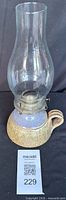 Full view of lamp showing glass chimney, burner, and ceramic base
