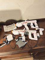 Full set laid out on table: 2 rifles, 2 pistols, 2 sensor packs, manual
