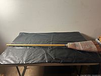 Full view of broom showing long wood handle and bristle head