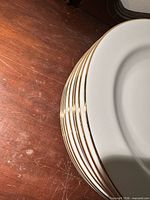 Stack of eight white plates showing gold trim edges