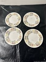 Set of four matching floral porcelain plates on black background