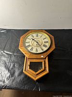 Front view of octagonal dial and oak case wall clock