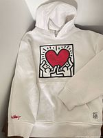 Full view of white Keith Haring hoodie showing front graphic, hood and pocket