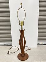 Full view of table lamp front showing wood base, brass column, socket and harp