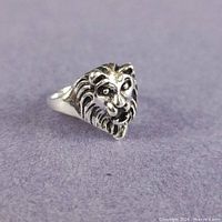 Oblique view of silver-plated lion head ring on fabric surface