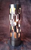 Full view of stainless-steel cylindrical light sculpture illuminated