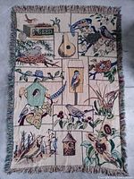 Full view of woven cotton tapestry throw with garden bird scene and fringe
