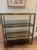Tall brass etagere with four smoked glass shelves