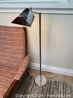 Full view of chrome floor lamp beside chair