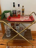 Front view of brass bar cart with two woodgrain shelves