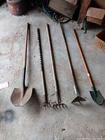 All five garden hand tools laid out on garage floor