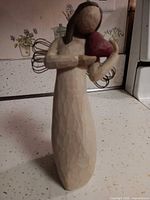 Front view of figurine showing heart, carved texture, and wire wings