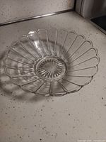 Top view of clear pressed glass candy dish showing scalloped rim and starburst base