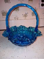 Overall view of blue glass basket showing handle and ruffled rim