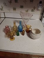 Group of nine assorted glass and ceramic decor pieces on countertop