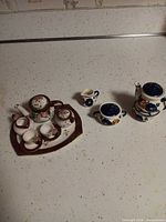 Overall view of both miniature porcelain tea sets and all components