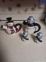 Two snowman teapots and two snowman shakers grouped on countertop