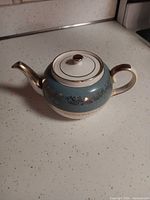 Side view of Sadler ceramic teapot showing blue band, gold trim, handle and spout