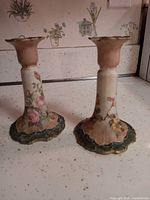 Front view of both candlesticks showing floral decoration and green scalloped bases