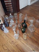 Group of assorted vintage glass bottles and jars on hardwood floor