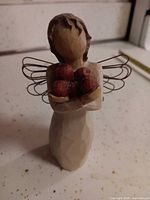 Front view of figurine showing apples and wings